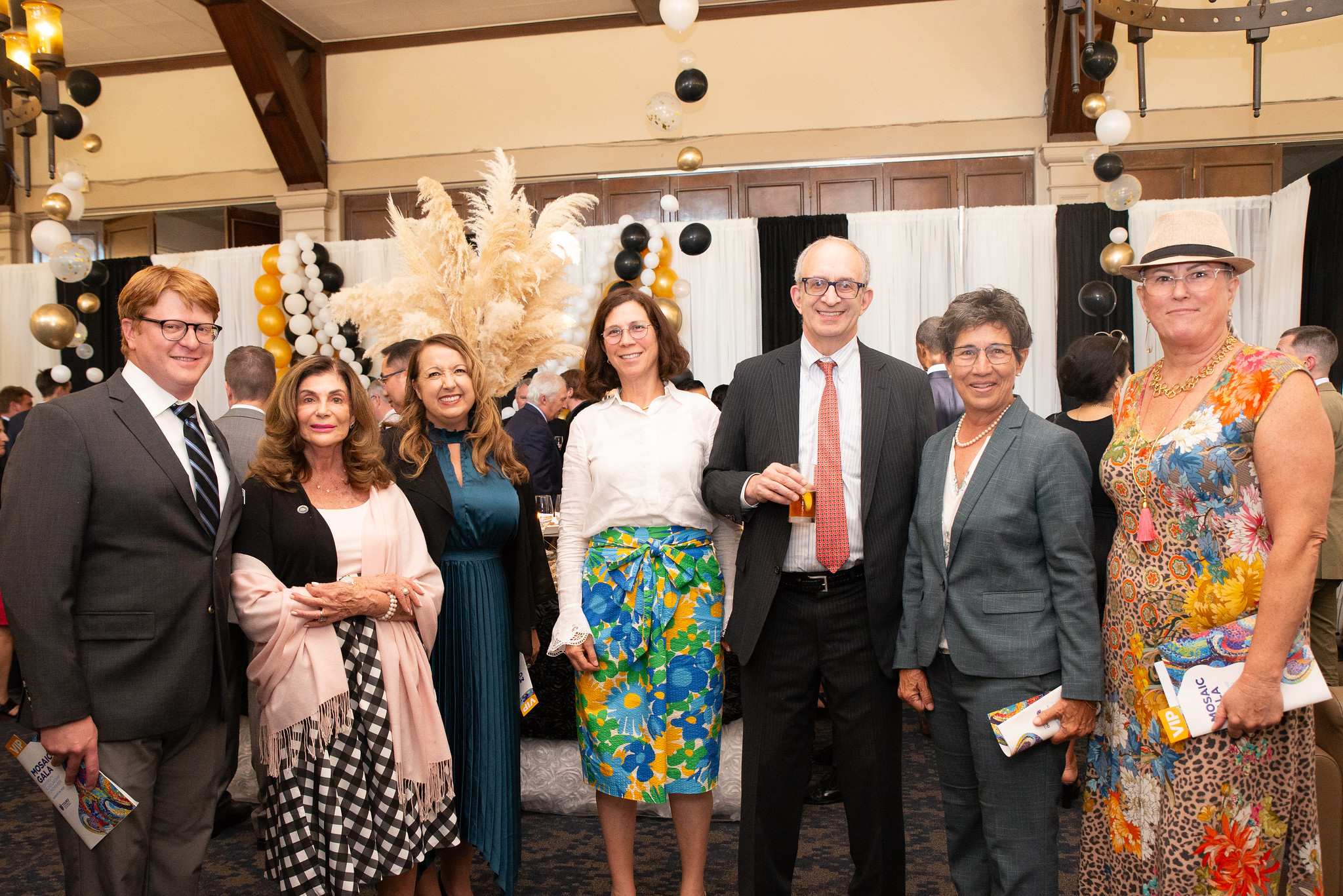 Seven people dressed up at a party standing and smiling