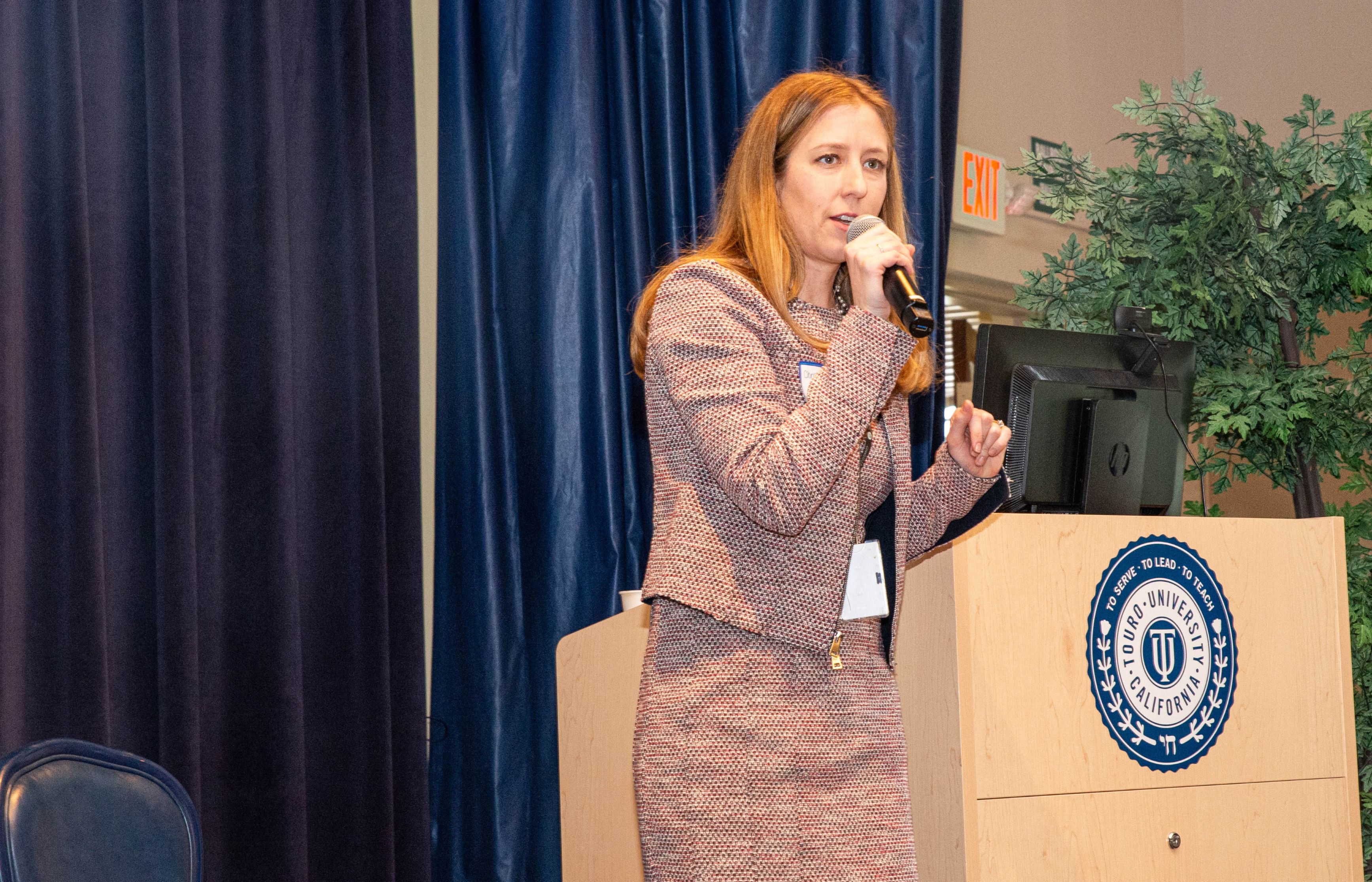  Dr. Christine Kinnevey Greig at a podium speaking into a microphone