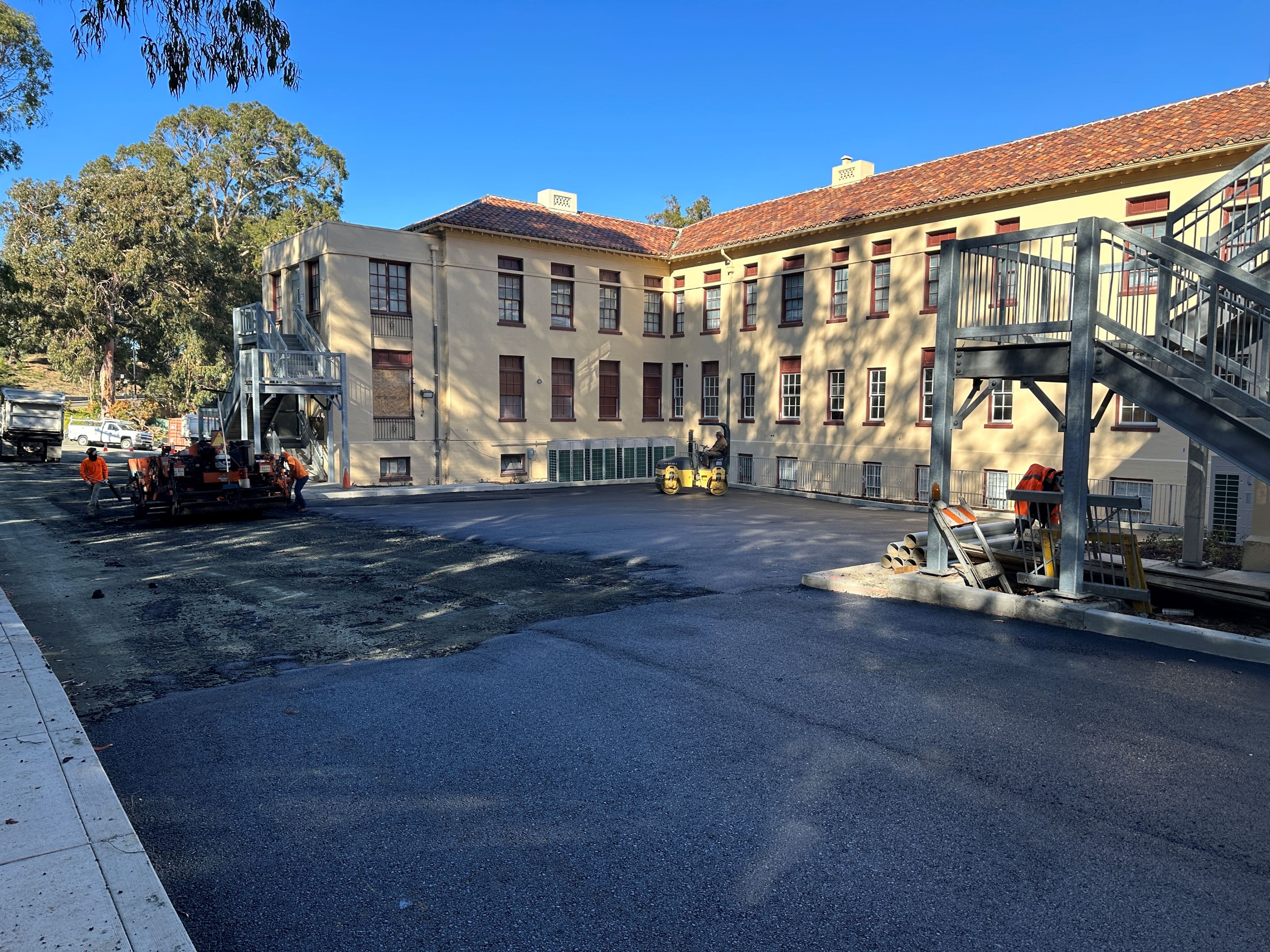 Exterior of Truett Hall, with workers putting down asphalt down on the exterior