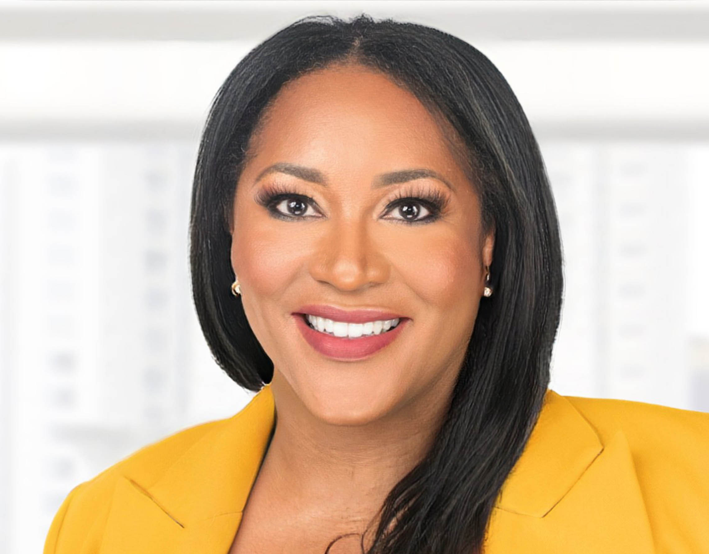 Dr. Karris Clarke standing and smiling, wearing a bright yellow suit