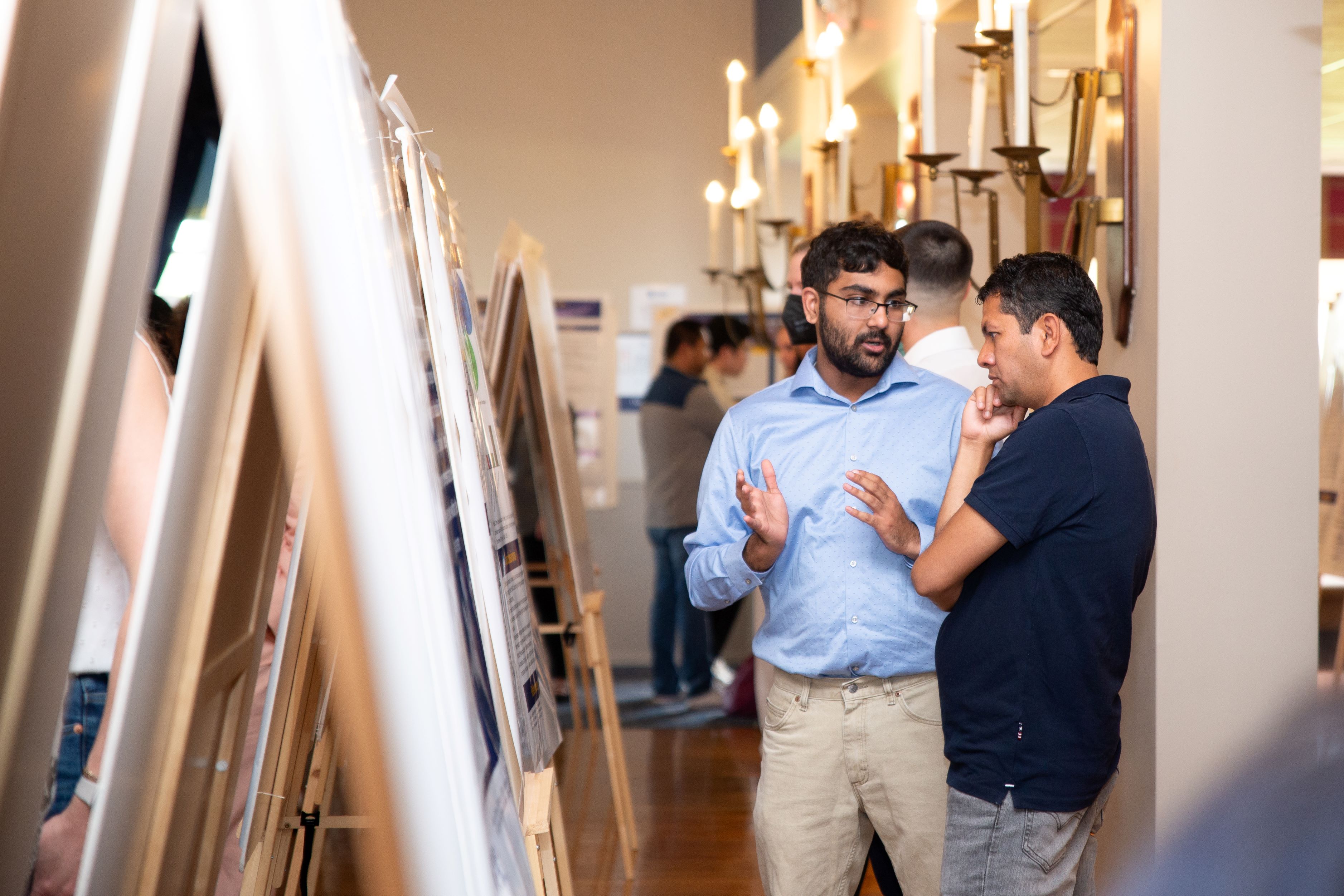 Two TUC students discuss research work inside Farragut Inn\'s ballroom