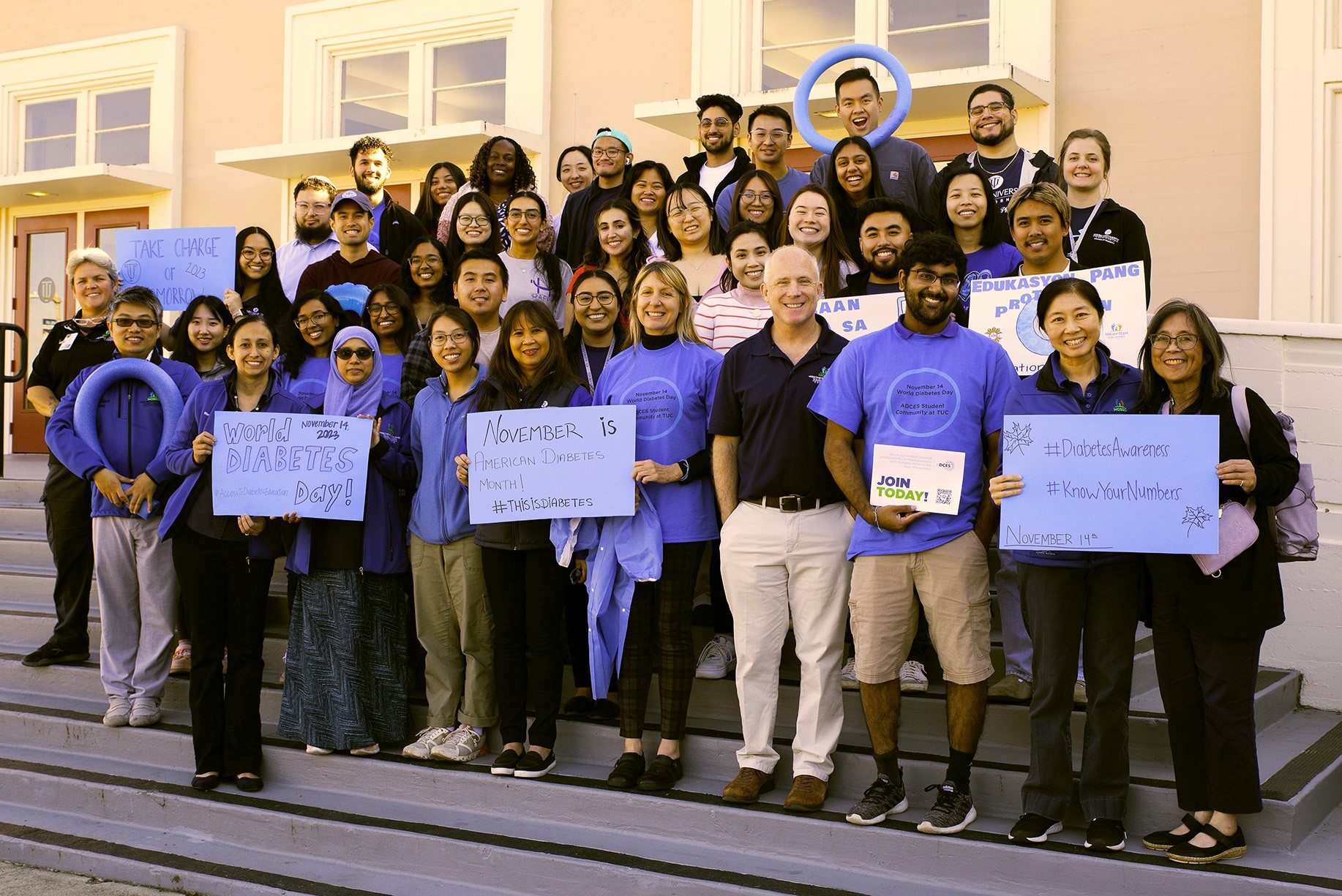 Group of people on steps raising awareness for Diabetes Day by wearing blue shirts