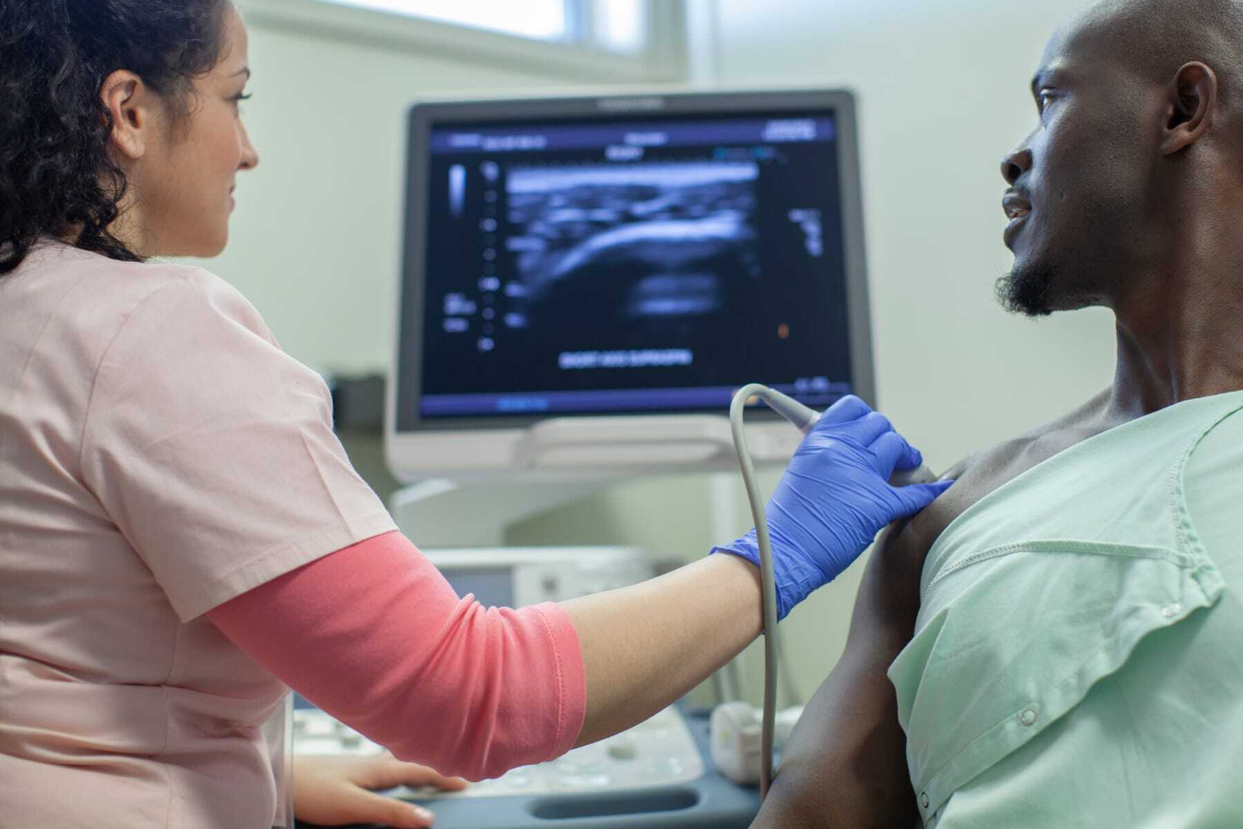 Woman taking a sonogram of a man\'s chest