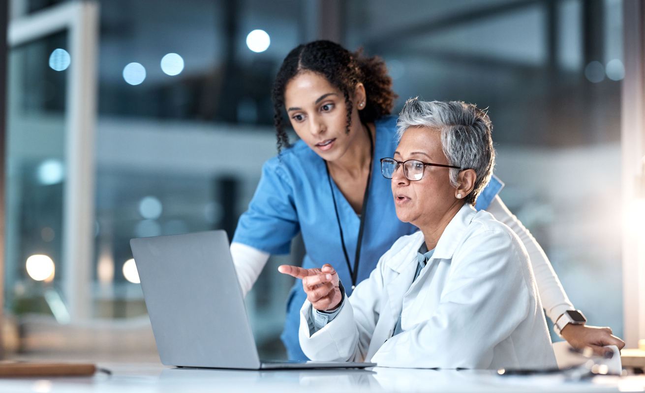 A doctor and a nurse look into a computer screen in a clinic or hospital