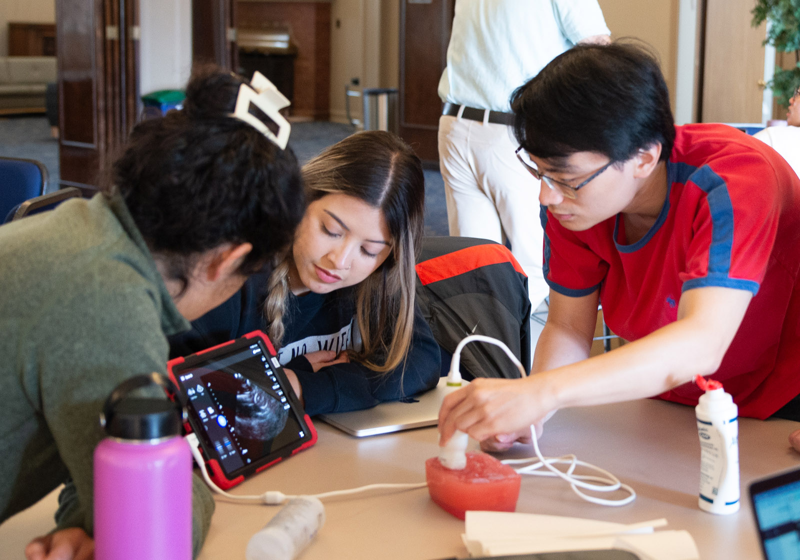 Students gather around a table analyzing the results of a sonogram