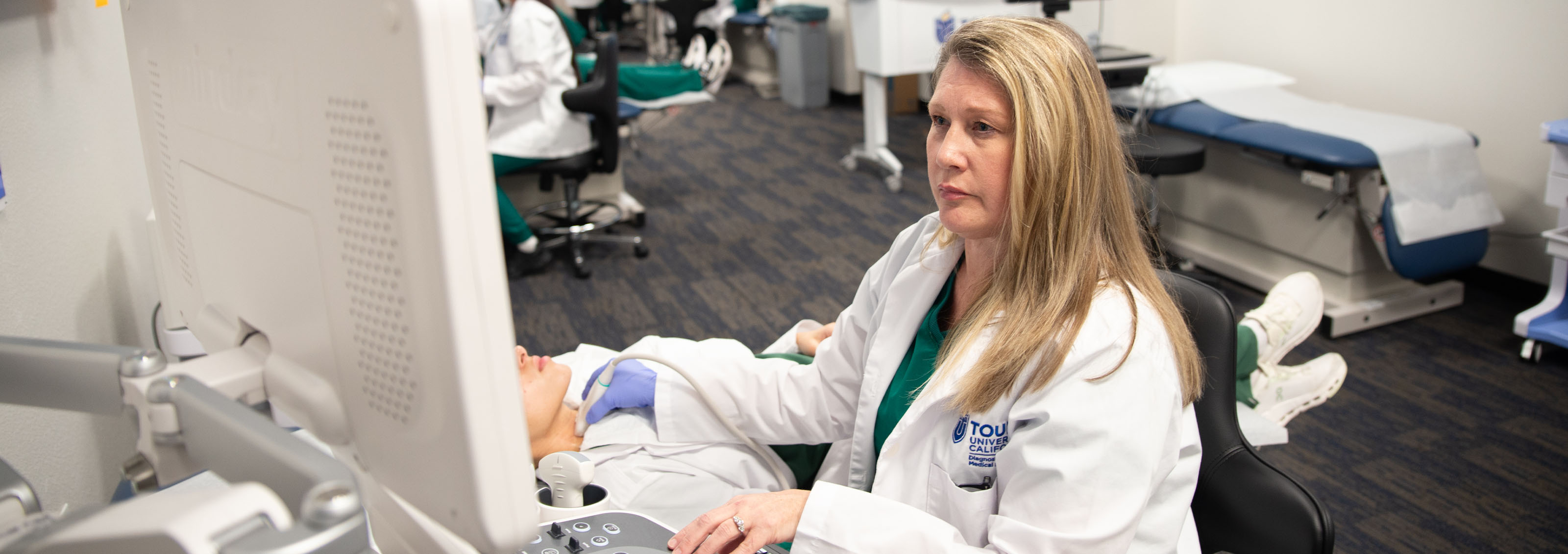 A Touro California Sonography student analyzes her monitor results of the sonogram she is giving to a patient.