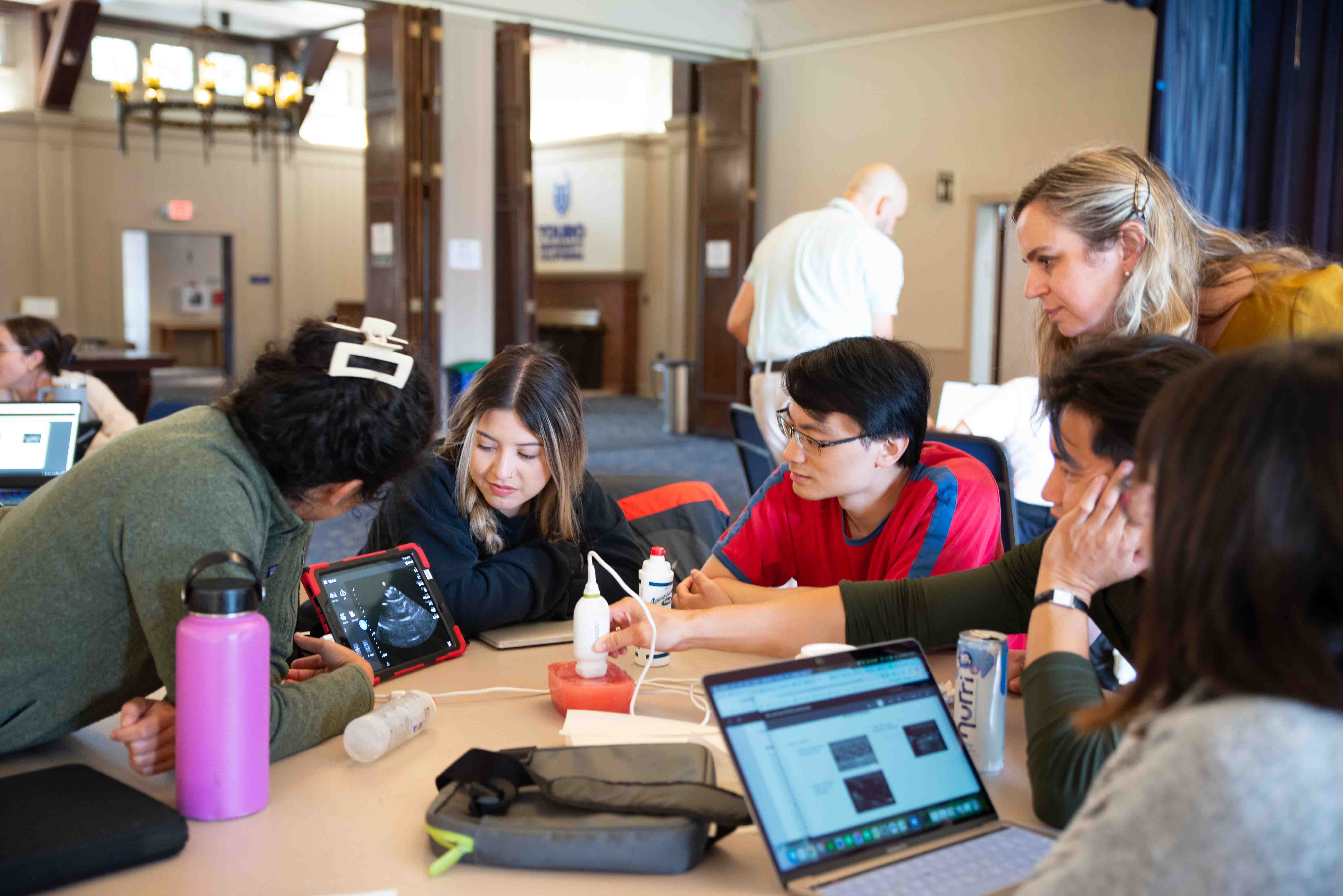 MSPAS/MPH Students join around a table to view live ultrasound imaging.