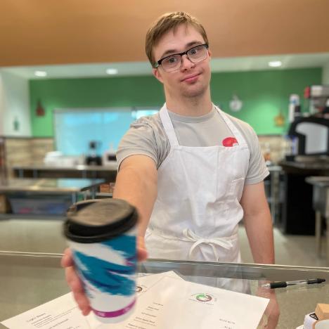 Tristan Lee hands a cup of coffee over the counter