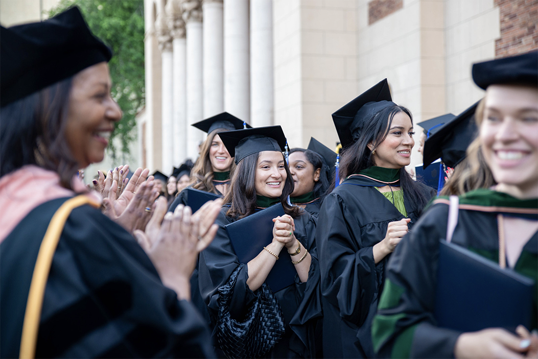A photo shows graduates of the College of Education and Health Sciences smiling as they pass by cheering faculty members after a Commencement ceremony May 20 at the Sacramento Memorial Auditorium.