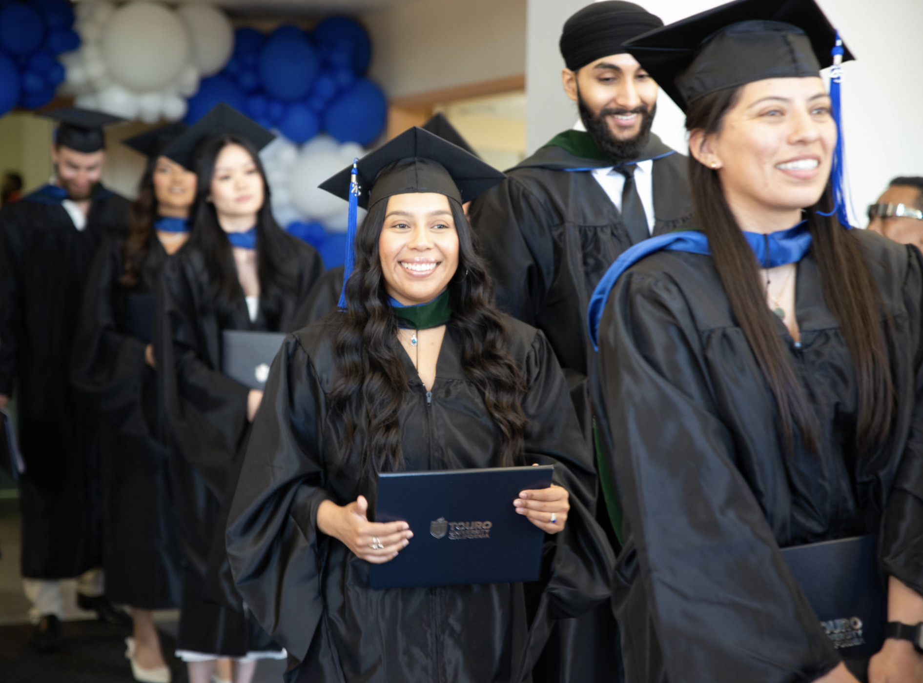A photo shows members of the Master of Science in Medical Health Sciences program smiling as they exit Lander Hall following a Commencement ceremony, Thursday, May 22, 2025.