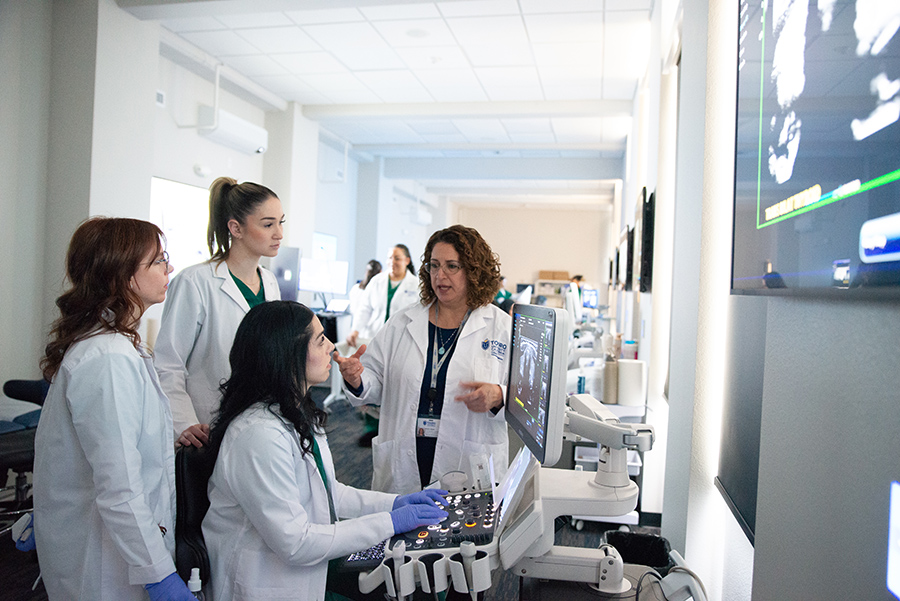 Diagnostic Medical Sonography students get hands-on with equipment while being lectured by a teacher