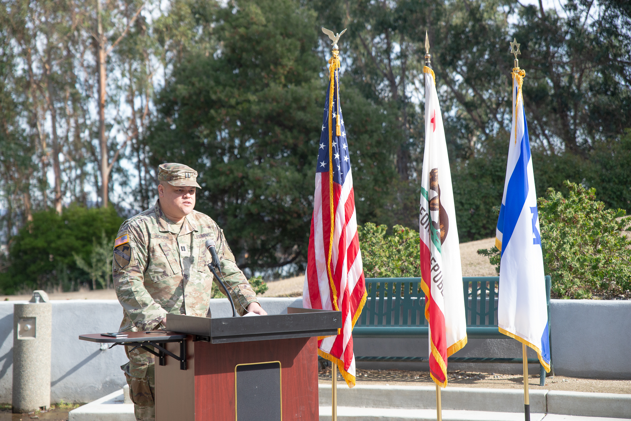 TUC graduate Captain Keith Jackson speaks at a podium at the Touro grave during a Veterans Day event.